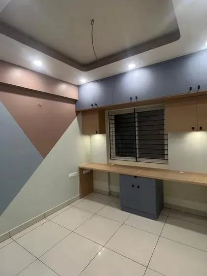 A kids' room with a long, built-in study desk for two. The geometric wall paint and overhead storage create a fun and functional space for homework and creative projects.