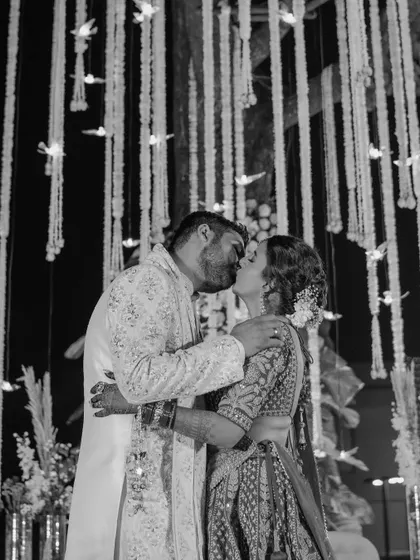 A passionate kiss under the dramatic lighting of the reception. This black and white photo is full of romance and energy.