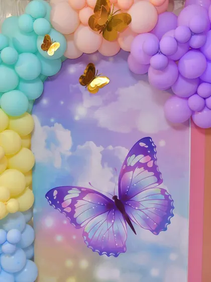A butterfly-themed backdrop panel with a large purple butterfly against a cloudy sky print.