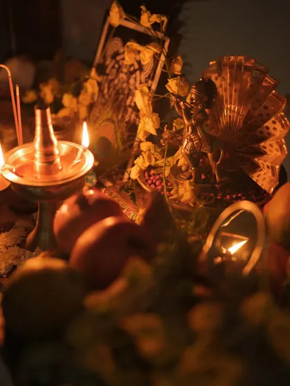 A close-up of the Vishu kani, with the warm glow of the vilakku illuminating the fruits and offerings. The focus is on the rich, traditional details.