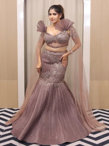 From engagement glam to reception shine, my fish-cut lehengas steal the show. This mauve gown with dramatic pleated shoulders is a true statement piece.