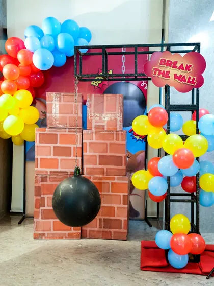 The 'Break the Wall' game, where participants use a wrecking ball to knock over a wall of fake bricks, themed for a Tom & Jerry party.