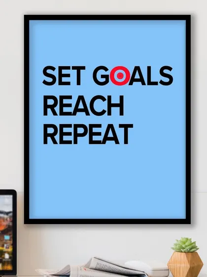 The "Set Goals, Reach, Repeat" print on a desk, serving as the perfect backdrop for a productive day. Its clean design and powerful message help keep you on track.