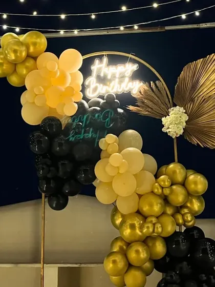 A close-up of the black and gold balloon arrangement with a dried palm leaf accent.
