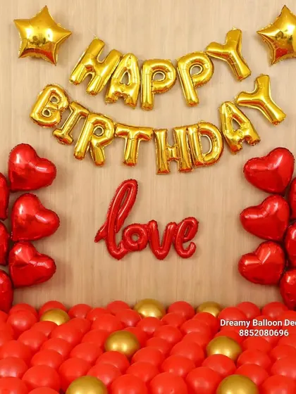 A bold and romantic birthday declaration. This wall is decorated with 'Happy Birthday' and 'Love' foil balloons, surrounded by red heart-shaped balloons and a floor of red and gold balloons.