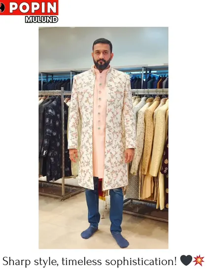 This client is trying on a layered sherwani look in our store. The combination of a light pink inner kurta with a floral embroidered off-white outer jacket is a popular choice for modern grooms.