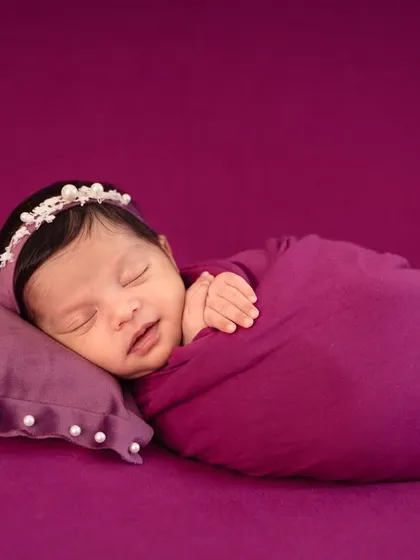 A simple yet elegant setup using a rich purple backdrop. The baby is peacefully asleep on a matching pillow, creating a cohesive and colorful portrait.