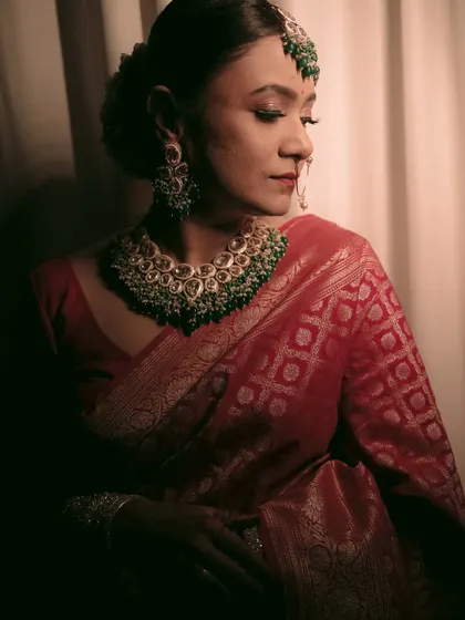 An elegant three-quarter portrait of the bride, showcasing her beautiful red silk saree and jewelry.