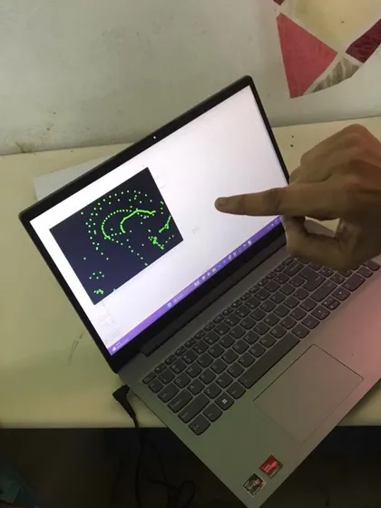An instructor points to a student's screen, which displays a program that generates a pattern using Python code.