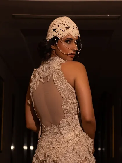 This updo was designed to work with a unique headpiece for a Vogue India editorial. The hair is gathered into a low, intricate bun, providing a secure and elegant base for the accessory.