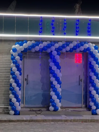 A blue and white balloon arch for the entrance of a new commercial establishment. This is a great way to welcome guests and customers for a grand opening.