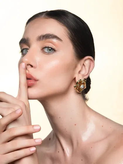 This pose adds a touch of mystery to the clean beauty look. The focus remains on the radiant skin and perfectly groomed eyebrows.