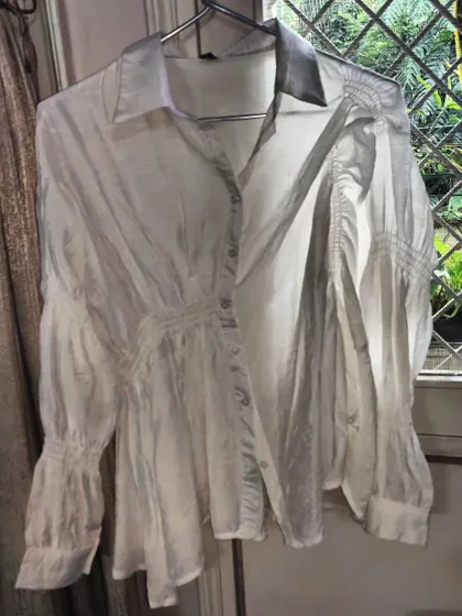 A white shirt is a wardrobe must-have. This one is an asymmetrical, free-size shirt made from the thinnest, pure cotton silk. The details in the smocking and cuffs make it a truly special piece.
