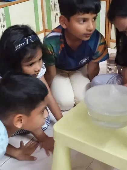 An instructor points out the changes happening inside the water cycle model to a group of young children.
