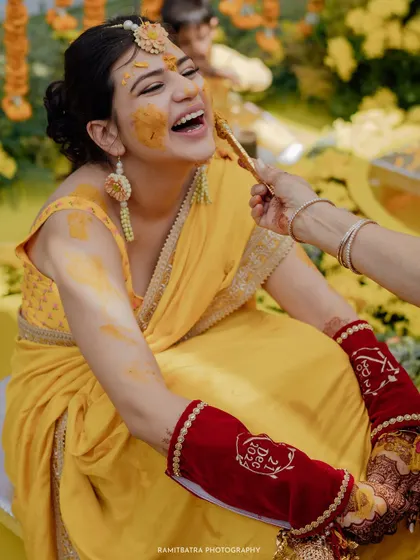 A candid shot of the bride laughing as a relative playfully feeds her during the Haldi ceremony.