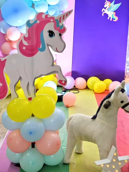A large unicorn cutout on a balloon pillar, part of a vibrant unicorn-themed party.