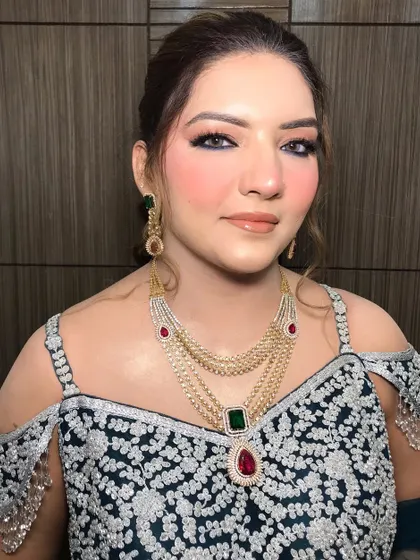 This party look features a stunning layered necklace with emerald and ruby drops, adding a pop of color to her embroidered outfit.