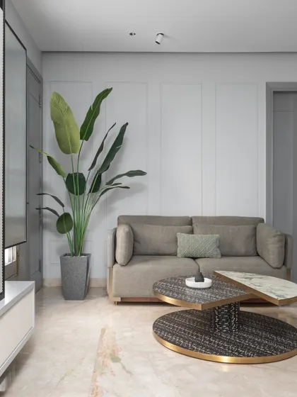 A detail shot of the lounge area within the master bedroom, featuring a unique layered coffee table and a comfortable sofa. The addition of a large plant brings a touch of nature indoors.