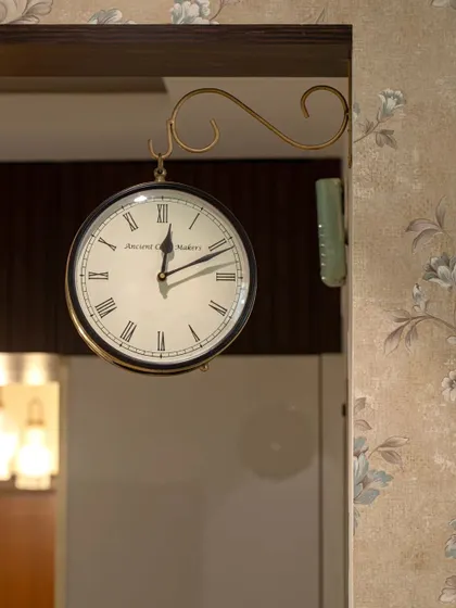 A close-up of the classic station clock and floral wallpaper in the 'Blue Elegance' project, showing how small details contribute to the overall timeless feel.