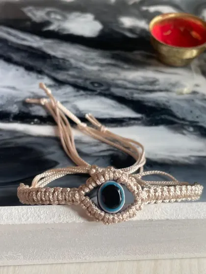 This handcrafted macrame bracelet features a protective evil eye charm. It's a meaningful and stylish piece, perfect as a Rakhi or a friendship band.