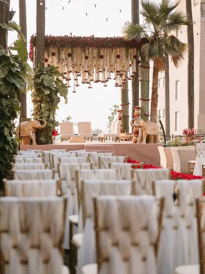 A grand traditional mandap at the Taj Lands End, flanked by statues of elephants and featuring a canopy of red and white florals.