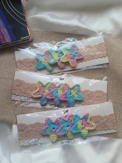 A set of three pastel rainbow star headbands for newborns, made with soft lace elastic for a comfortable fit.