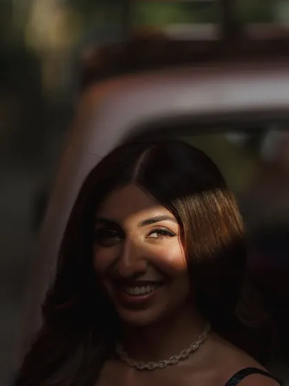 An artistic shot with a play of light and shadow, highlighting her bright smile and the sparkle in her eyes.