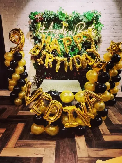 A unique backdrop combining a lush green wall with black and gold balloons. I can spell out any name or message with foil balloons to personalize the decoration for your birthday party.