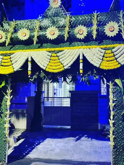 I created this traditional entrance arch for a home-based haldi ceremony using woven coconut leaves and garlands of yellow and white flowers. The banana plantain trunks on the sides are a classic element in South Indian decor.
