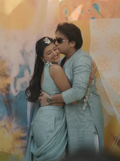 An affectionate moment between the couple, captured against the soft, watercolor-like patterns of the fabric backdrop.