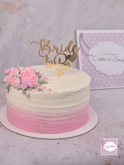 A lovely pink ombre cake with a spray of buttercream roses for a bridal shower.