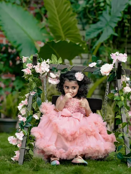 A sweet, shy expression from a little girl in a beautiful pink dress, sitting on our floral swing. We capture all the different moods of your child.