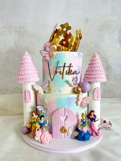 A castle cake fit for all the Disney princesses! This two-tier creation features pastel watercolor buttercream, pink castle turrets, and beloved characters like Cinderella, Ariel, and Belle.