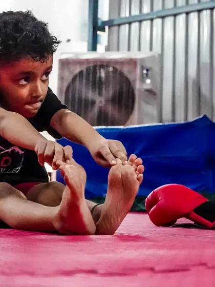 A focused young student stretching. Our kids' MMA program teaches athletic fitness, self-defense, and prepares them for a potential professional career.