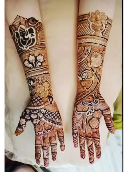 This design features a large Ganesh motif on one arm for blessings and good luck. The rest of the design is filled with floral and peacock elements.