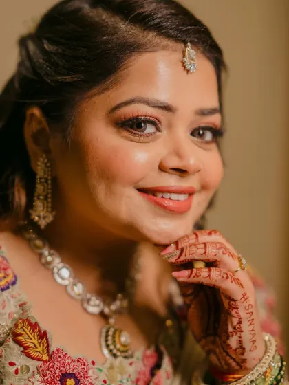 A close-up of the bride, highlighting her beautiful makeup and the personal touch of her husband's name written in her henna.