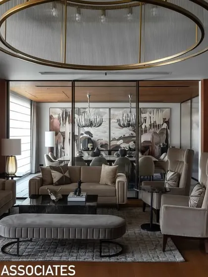 Another view of the living room, showcasing the arrangement of bespoke furniture, including high-back chairs and a plush ottoman, designed for both style and comfort.