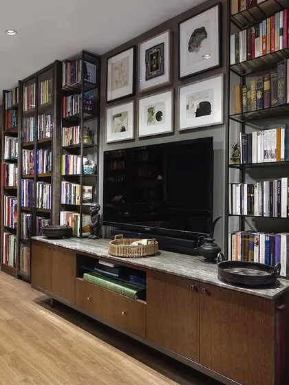 The study features a custom media unit integrated into the bookshelves, with a collection of monochromatic drawings by Anil Revri and Krishen Khanna displayed above. This shows how we blend technology, art, and storage seamlessly.