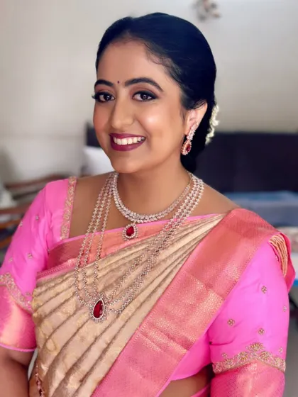 Dr. Sandhya looking radiant for her engagement. The makeup features a soft smokey eye and a berry lip, beautifully complementing her pink and gold saree and diamond jewelry.