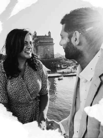 A bright, high-contrast black and white photo capturing a happy moment with the Gateway of India in the background. The sun flare adds a touch of magic.