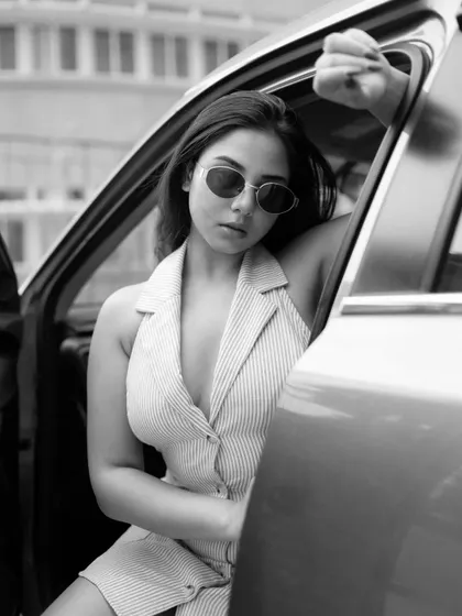 A black and white version of a car portrait. The monochrome treatment adds a timeless, classic feel to the shot, emphasizing the model's expression and the composition.