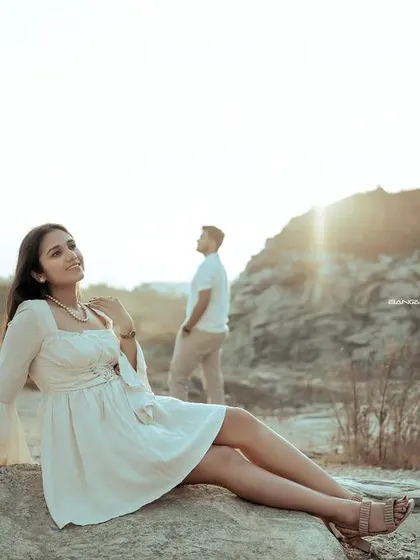 The bride-to-be basks in the golden hour light, while her partner stands in the background. This creative composition tells a story of love and anticipation.