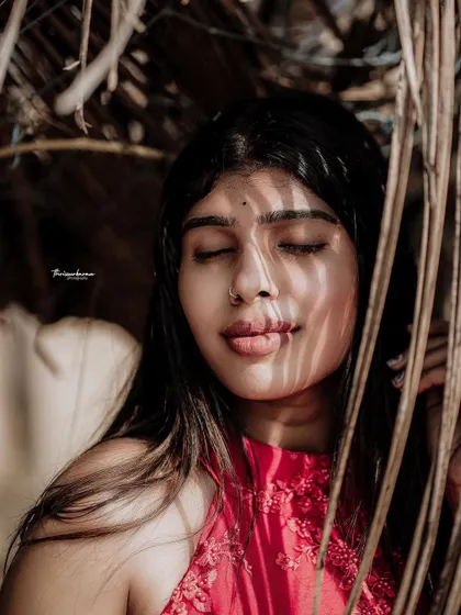 A close-up creative portrait using dried palm leaves to frame the face and create interesting shadow patterns. This is a great technique for adding texture and depth.