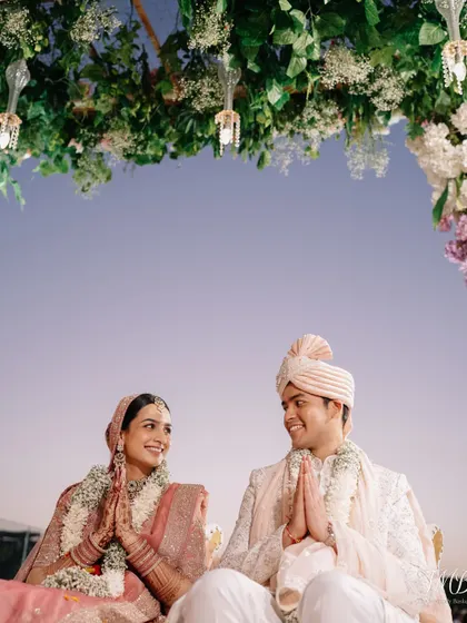 The serene moments just before the pheras begin, with the couple sharing a look of love and anticipation under a canopy of flowers.