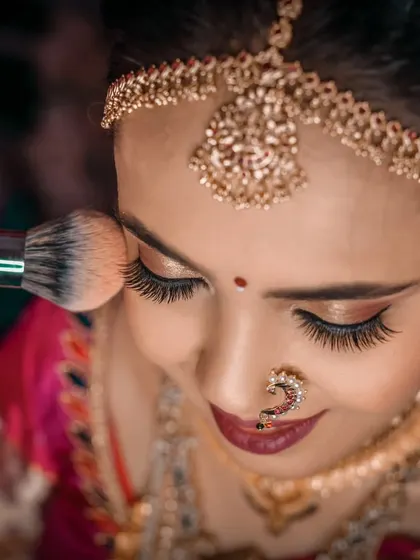 A close up shot of the bride getting her final makeup touches, highlighting the detail and anticipation before the ceremony.
