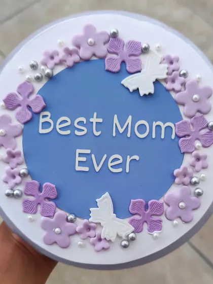 A "Best Mom Ever" cake decorated with purple flowers and white butterflies. A beautiful way to show your appreciation.