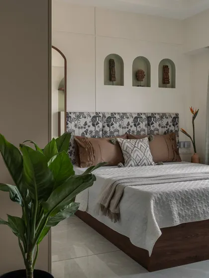A closer look at the bedroom, focusing on the custom headboard with its unique print and the arched wall niches that display curated decor pieces, adding a personal touch.
