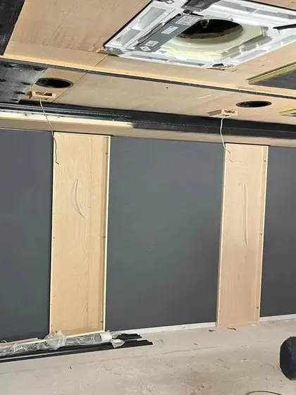 The walls are up. This photo shows the room after the main drywall and paneling are in place, but before the final finishing touches like fabric, paint, and seating are added.