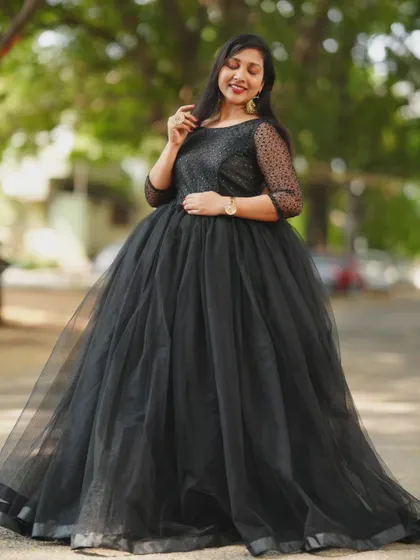A classic black ball gown made of soft tulle with sheer, dotted sleeves. This is a timelessly elegant choice for an evening photoshoot, offering a sophisticated and dramatic look.