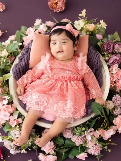 A beautiful portrait of a baby girl in a pink lace dress, nestled among flowers for her milestone session.